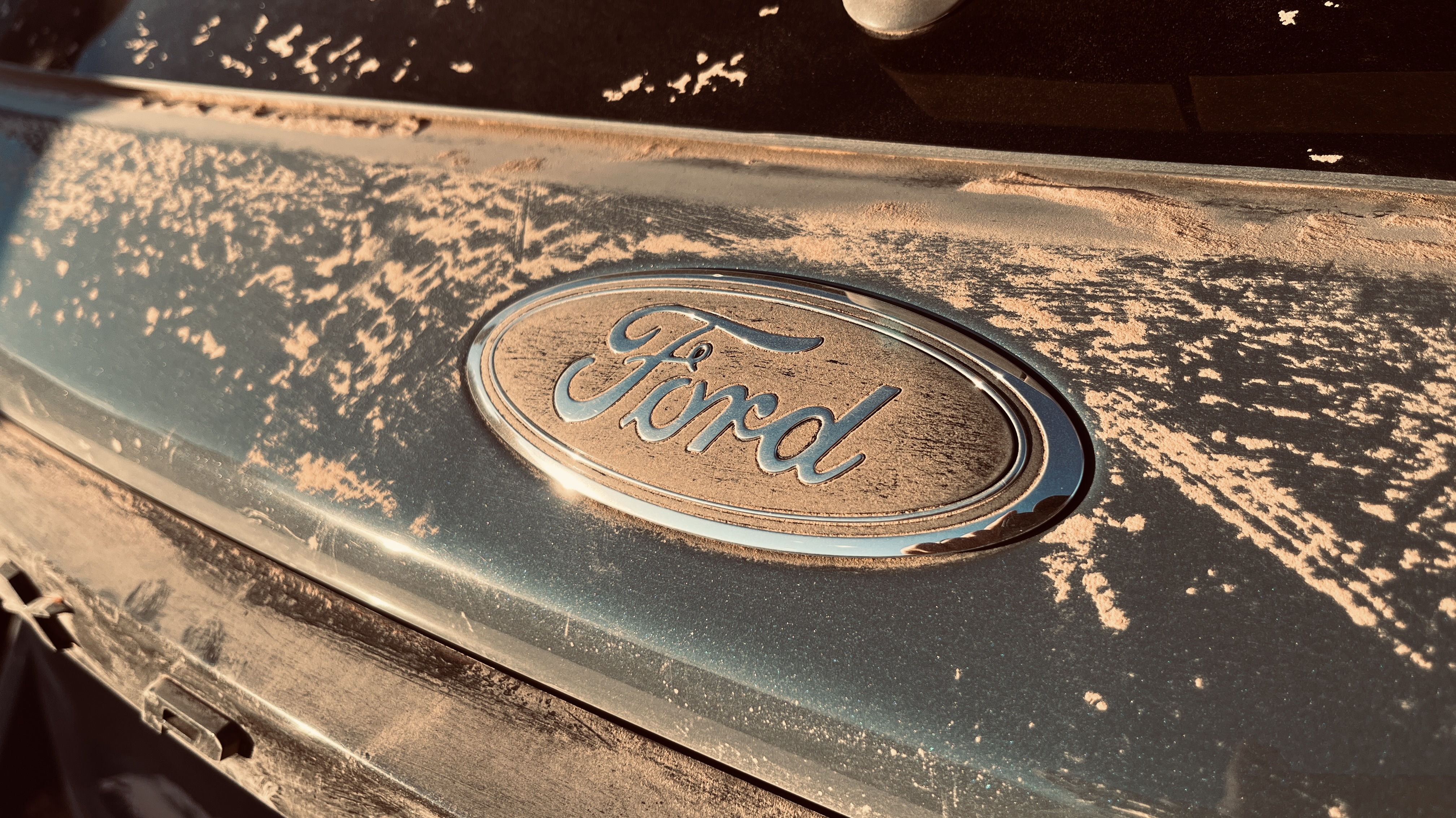 The "Ford" nameplate on an Exlorer covered in dirt.